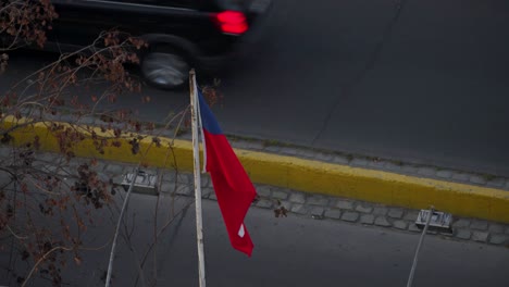 Flag-Of-Chile-Flying-In-The-Wind-With-Passing-Vehicles-In-Background