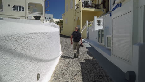 Following-a-man-walking-down-a-narrow-street-in-Santorini-island