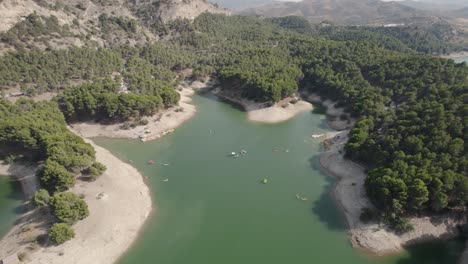 Drone-view-of-La-Isla-el-Chorro-featuring-small-boats-surrounded-by-aromatic-pine-forest-of-the-Malaga-lake-district-in-Andalusia-Spain