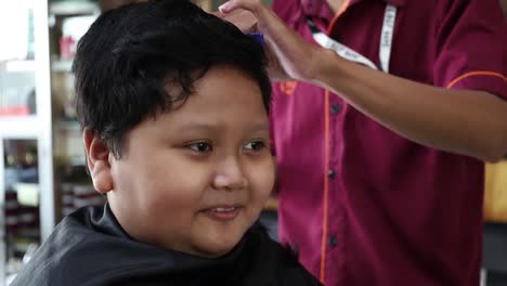 Entzückender-Glücklicher-Asiatischer-Junge,-Der-Frisur-Im-Friseursalon-Bekommt