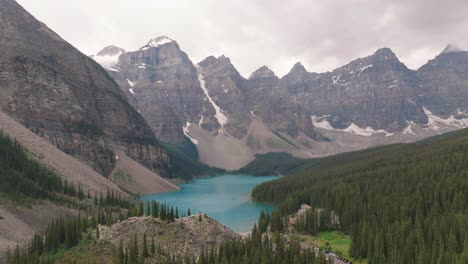 Aerial-truck-left-of-emerald-Lake-Moraine-between-pine-tree-forest-and-Canadian-Rockies-at-Banff-National-Park,-Alberta,-Canada