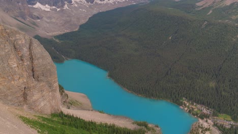 Aerial-dolly-out-of-emerald-Lake-Moraine-between-pine-tree-forest-and-Canadian-Rockies-at-Banff-National-Park,-Alberta,-Canada
