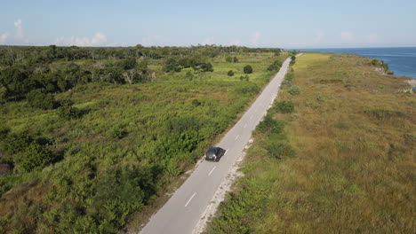 Aerial-View-Of-A-Car-Driving-Through-Coastal-Road-On-A-Sunny-Day-In-Sumba-Island,-Indonesia