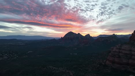 Adventurous-Female-Hiker-Standing-At-The-Edge-Of-A-Steep-Cliff,-Admiring-Picturesque-Sunset-Over-Sedona,-Arizona