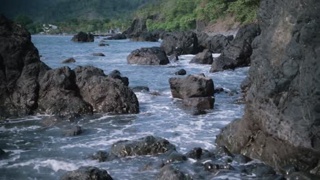 Wellen,-Die-Gegen-Felsen-Mit-Tropischer-Küste-Im-Hintergrund-Krachen