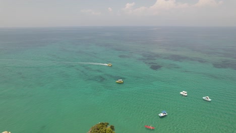 Aerial-orbit-over-Turquoise-Seascape-with-tour-boats-at-Sidari-Coastline,-Corfu-Island,-Greece