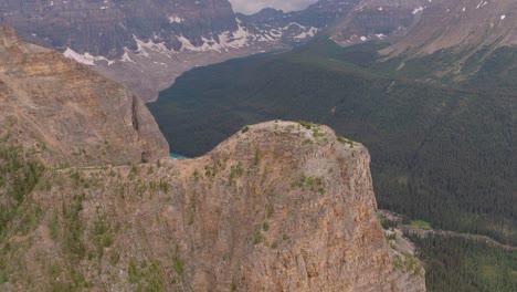 Aerial-dolly-in-of-emerald-Lake-Moraine-between-pine-tree-forest-and-Canadian-Rockies-at-Banff-National-Park,-Alberta,-Canada