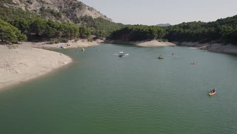 Luftaufnahme-Des-Sees-El-Chorro-In-Málaga,-Umgeben-Von-Pinien,-Mit-Touristen,-Die-Bootfahren-Und-Wassersport-Genießen