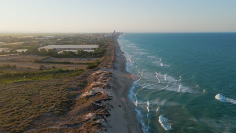 Aerial-view-of-the-coastline-at-Mareny-beach-with-kitesurf-kites-during-sunset-Valencia,-Spain