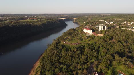Rückwärtiger-Drohnenflug-Mit-Blick-Auf-Hotel-Und-Park-Am-Fluss-Iguazu-In-Misiones-An-Der-Argentinien-brasilien-Grenze