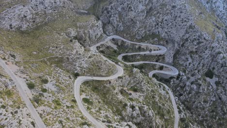 Revealing-shot-of-the-hairpin-bends-and-mountain-road-at-Sa-Calobra,-Mallorca,-Spain