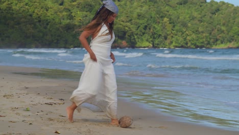 Young-girl-in-beach-dress-kicks-a-coconut-around-on-the-beach