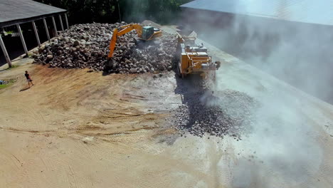 Drone-shot:-Rising-dust-in-air-during-construction-site-work-with-digger-and-conveyor