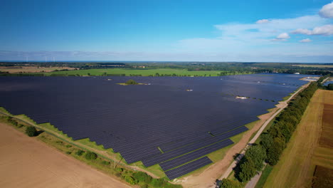 Solar-Photovoltaic-Farm,-Drone-Aerial-Flying-Over-Massive-Solar-Panel-Array-FIeld-in-Poland-on-a-Sunny-Day