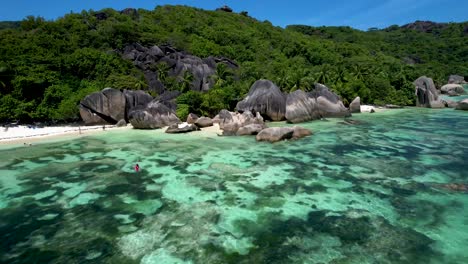 Aerial-view-of-Anse-Source-D'argent-beach-in-the-Seychelles-with-iconic-boulders-and-woman-kayaking
