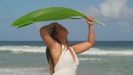Pretty-young-female-shades-under-a-palm-leaf-on-a-tropical-beach