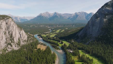 Aerial-rising-over-Bow-River-surrounded-by-pien-forest-and-Canadian-Rockies-mountain-range-at-Banff-National-Park,-Alberta,-Canada