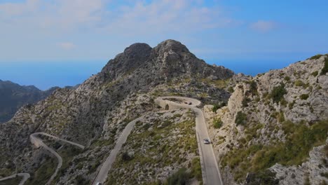 Following-a-car-on-a-winding-mountain-road-on-a-beautiful-day-with-clear-blue-sky-at-Sa-Calobra,-Mallorca,-Spain