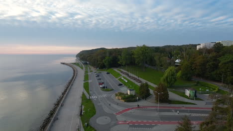 Sunrise-over-the-seaside-boulevard-in-Gdynia,-slightly-overcast-sky,-individual-passers-by-strolling-along-the-seafront