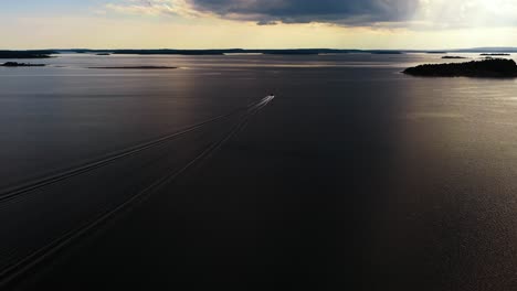 Aerial-view-of-a-boat-driving-in-the-Aland-archipelago,-dramatic-sunset-in-Finland
