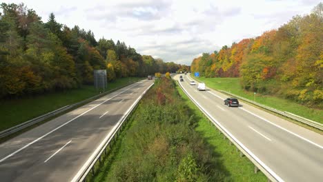 Blick-über-Eine-Autobahn-Mit-Fahrenden-Autos,-Eingerahmt-Von-Herbstfarbenen-Bäumen,-Dynamischer-Zoom