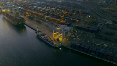 Aerial-view-of-cranes-unloading-container-ship-in-the-port-at-night,-Oakland-USA