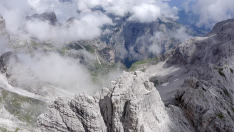 Aerial-shot-of-mountaintop-of-Brenta-Dolomites-during-sunny-day-with-hovering-clouds-in-summer