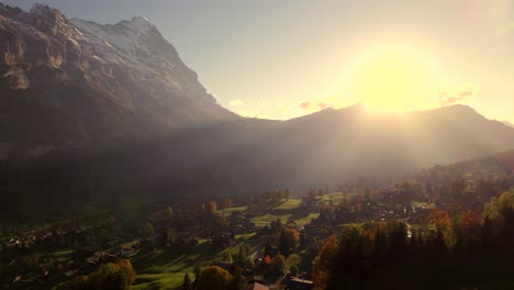 aerial-drone-footage-pushing-in-right-to-left-over-Grindelwald-village-with-spectacular-sunset-view-of-Eiger-North-Face,-Switzerland