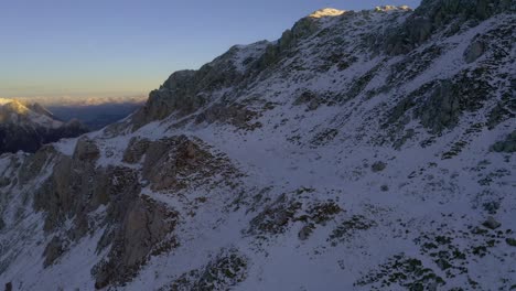 Majestic-drone-flight-over-snowy-peak-of-Viezzena-Mountain-in-Dolomites-during-golden-sunrise
