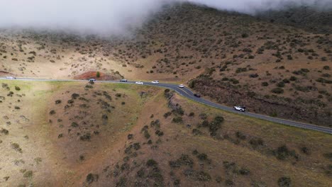 Tourists-drive-up-Haleakala-volcano-through-clouds-toward-the-national-park-on-winding-mountain-road