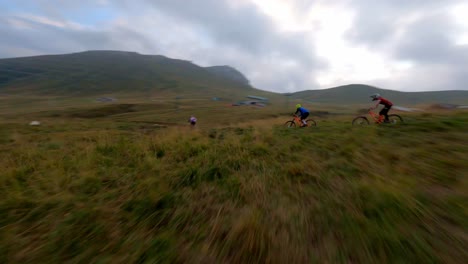 Spectacular-drone-flight-following-group-of-mountain-biker-riding-downhill-the-mountain-path