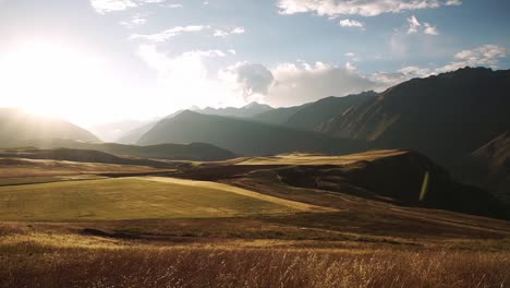 Sonnenaufgang-über-Dem-Malerischen-Heiligen-Tal,-Der-Das-Getrocknete-Gras-Golden-Glühen-Lässt-Und-Das-Ganze-Tal-Mit-Lichtstrahlen-Erhellt,-Chincheros,-Cusco