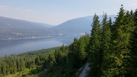 Aerial-footage-flying-through-a-mountainous-landscape-covered-by-coniferous-forest-canopy-above-shuswap-lake-during-wildfire-season