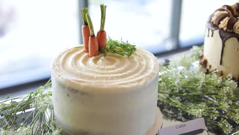 Wedding-cake-decorated-with-frosting,-carrots-and-yarrow-on-metal-tray