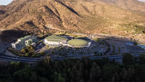 Cinematic-aerial-hyper-lapse-of-Monticello-casino-surrounded-by-trees-and-mountains-range-just-before-the-sunset,-Rancagua,-Chile