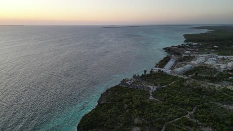 Hotel-resorts-at-Kusini-beach-Zanzibar-Island-Tanzania-Africa-with-sunset-over-ocean,-Aerial-pan-left-reveal-shot