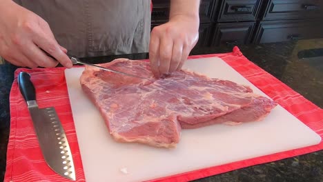Person-is-cutting-off-muscle-and-fat-tissue-from-pork-meat-with-sharp-knife