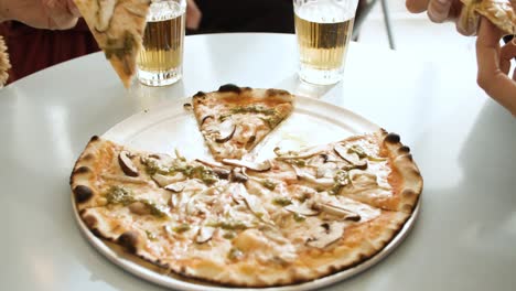 People-are-sitting-on-the-table-and-sharing-a-pizza-and-having-few-glasses-of-drink