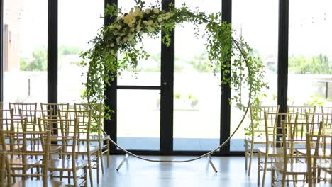 Circular-floral-wedding-altar-and-glass-wall-behind,-dolly-shot