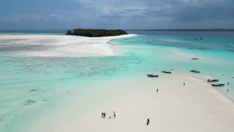 Mnemba-island-of-Zanzibar,Tanzania-Africa-with-snorkeling-tour-boats-and-visitors-on-the-sandy-beach,-Aerial-dolly-left-shot