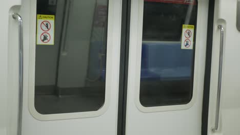 An-interior-selected-focus-view-at-window-on-subway's-door,-view-of-the-doors-on-a-commuter-subway-car-while-train-is-moving