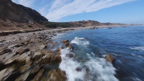 Cinematic-FPV-drone-flying-close-to-the-shore-of-Chilean-coastal-sea-turquoise-water-with-rocky-landscape-in-daytime