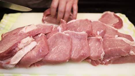 Butcher-is-cutting-raw-pork-meat-with-sharp-knife-and-using-hand