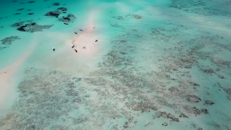 Arrecife-De-Coral-En-El-Atolón-De-La-Isla-De-Mnemba-En-Zanzíbar,-Tanzania,-áfrica-Con-Botes-Turísticos-De-Esnórquel,-Tiro-De-Revelación-De-Inclinación-Aérea-Hacia-Arriba