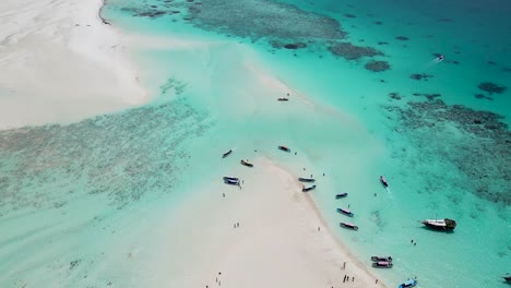Atoll-at-Mnemba-island-of-Zanzibar,Tanzania-Africa-with-snorkeling-tour-boats-on-the-reef-beach,-Aerial-dolly-up-shot