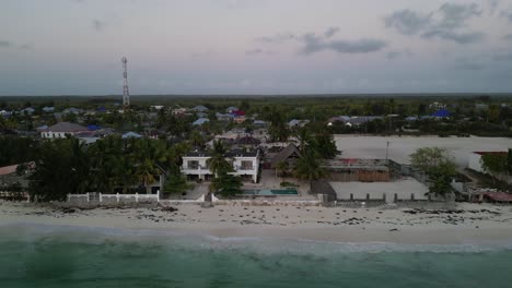 Uroa-beach-homes-and-bungalows-in-Zanzibar-Island-Tanzania-Africa,-Aerial-top-view-dolly-out-reveal-shot