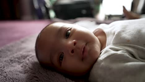Entzückender-2-Monate-Alter-Indischer-Junge,-Der-Mit-Großen-Augen-In-Die-Kamera-Schaut,-Während-Er-Auf-Einer-Decke-Auf-Dem-Boden-Liegt