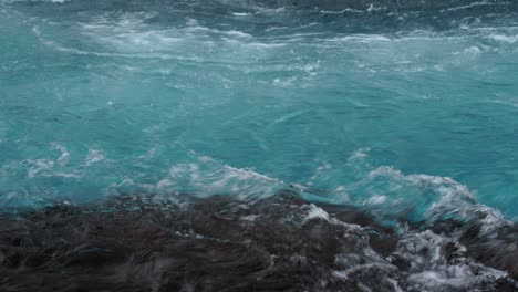 Powerful-blue-clear-water-of-river-flowing-between-shoreline-of-Iceland-during-daytime---close-up-panning-shot