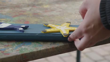 Teenager-glues-a-sawed-out-and-painted-wooden-star-onto-a-fence-rail