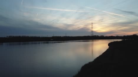 Sun-setting-down-over-majestic-river-of-Scheldt,-aerial-ascend-view